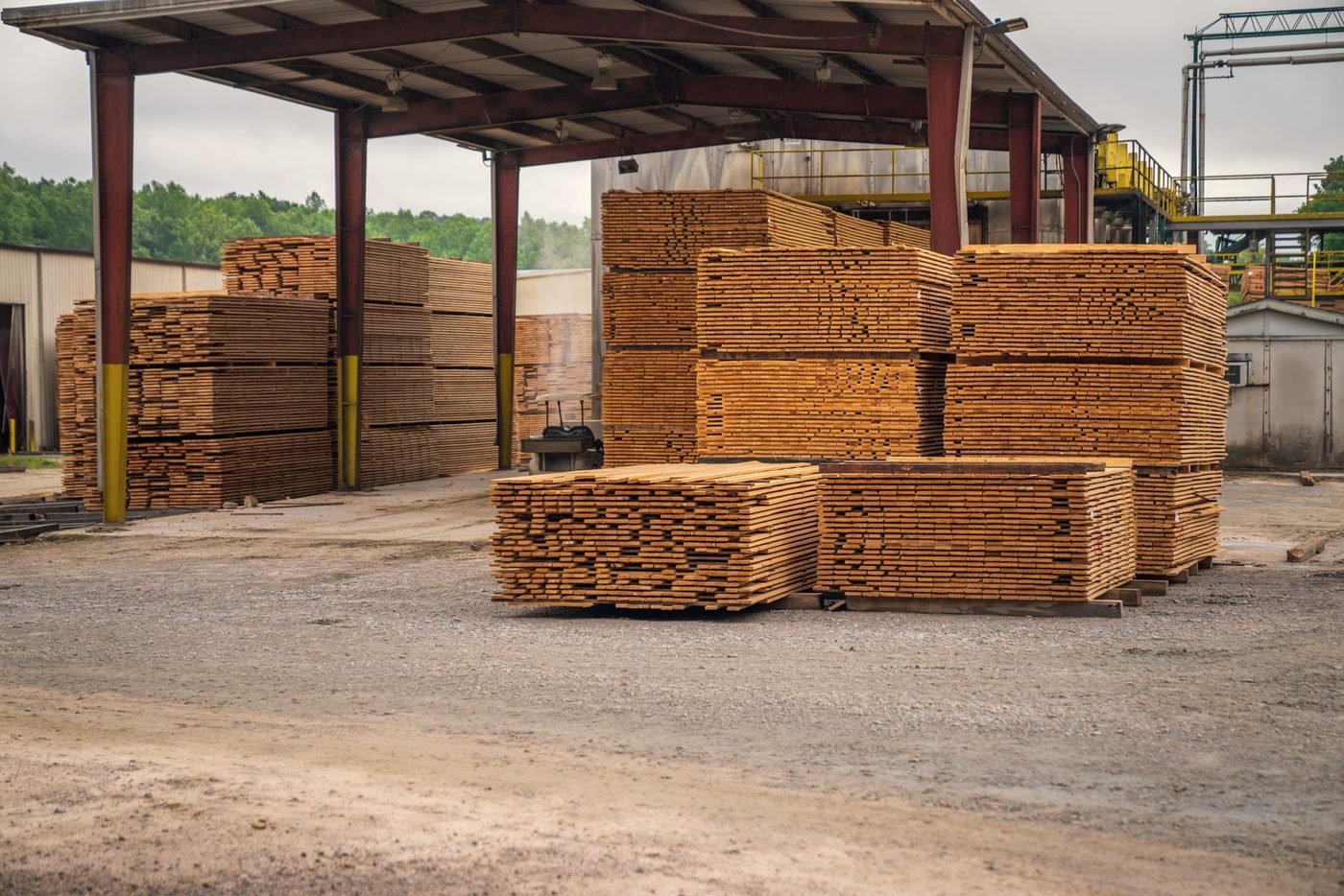 Open-sided lumber shed with banded units of boards stored out of the weather.
